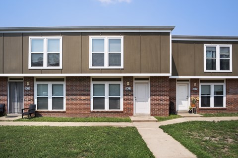 A row of townhouses with a sidewalk in front.