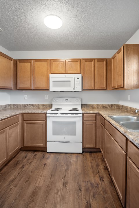 A kitchen with wooden cabinets and a white stove top oven.