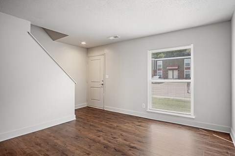 A room with wooden floors and a window showing a building outside.