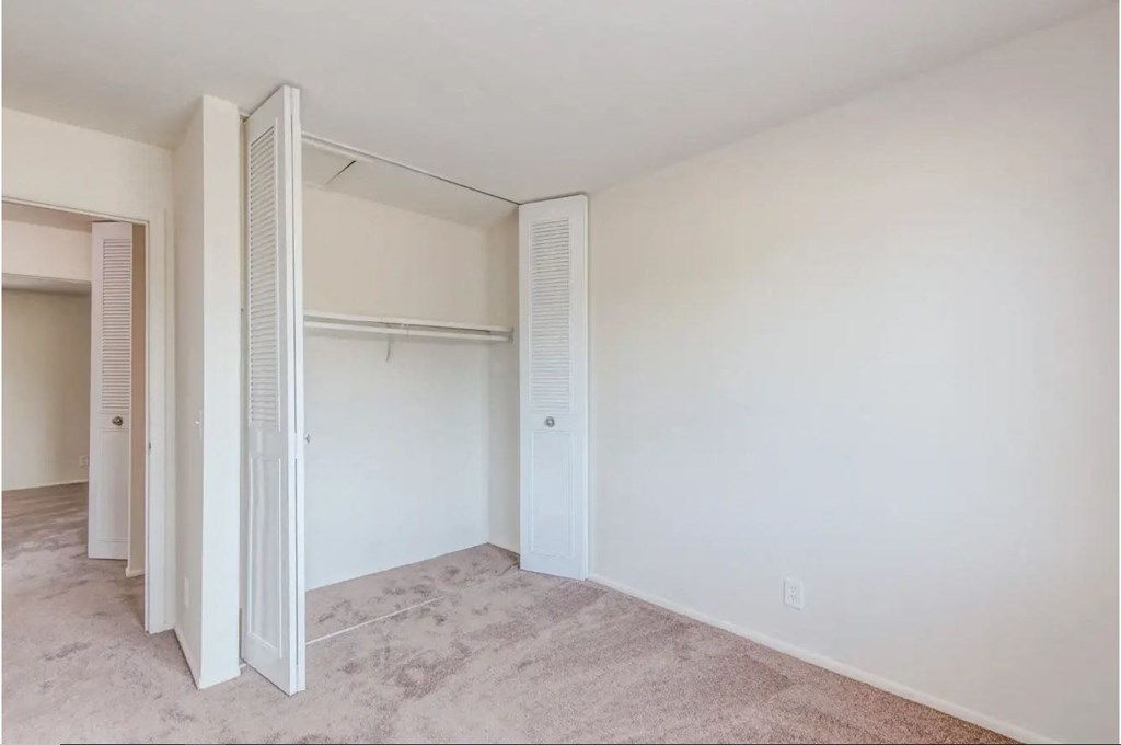 a bedroom with white walls and a closet with white doors
