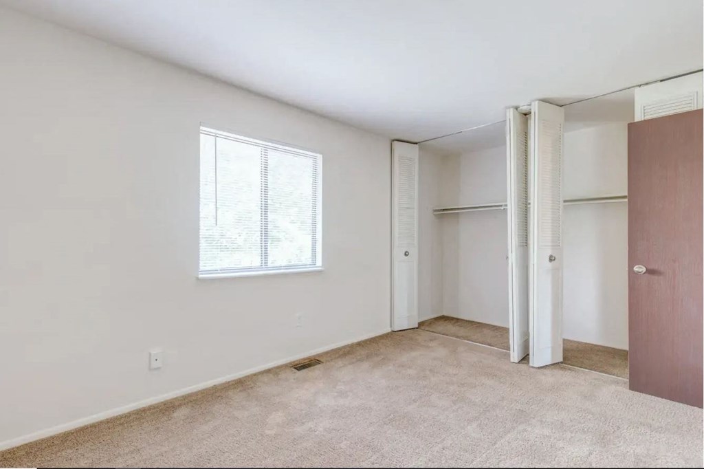 a bedroom with a large window and a door to a closet