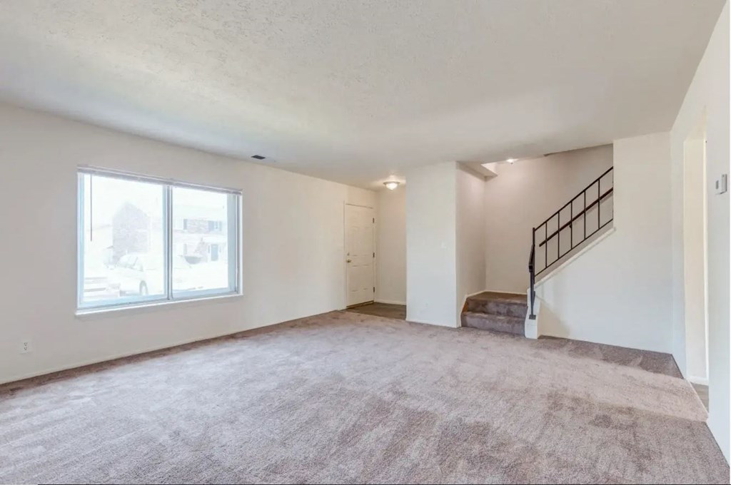 an empty living room with a staircase in the corner