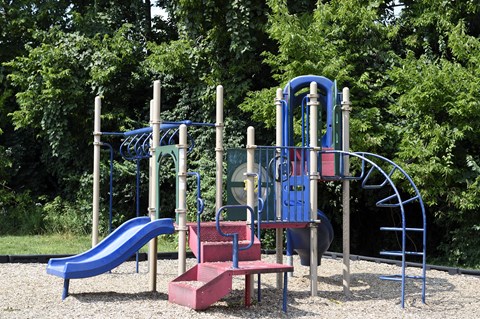 a playground with a blue slide and a red bench