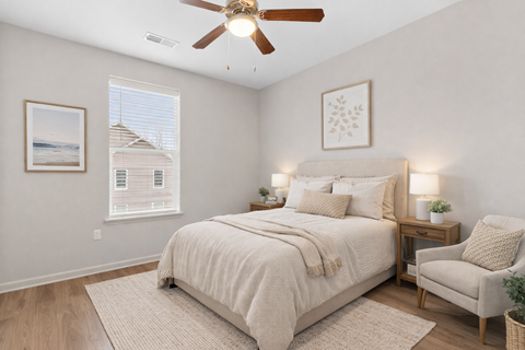 A bedroom with a large bed, a ceiling fan, and a chair.