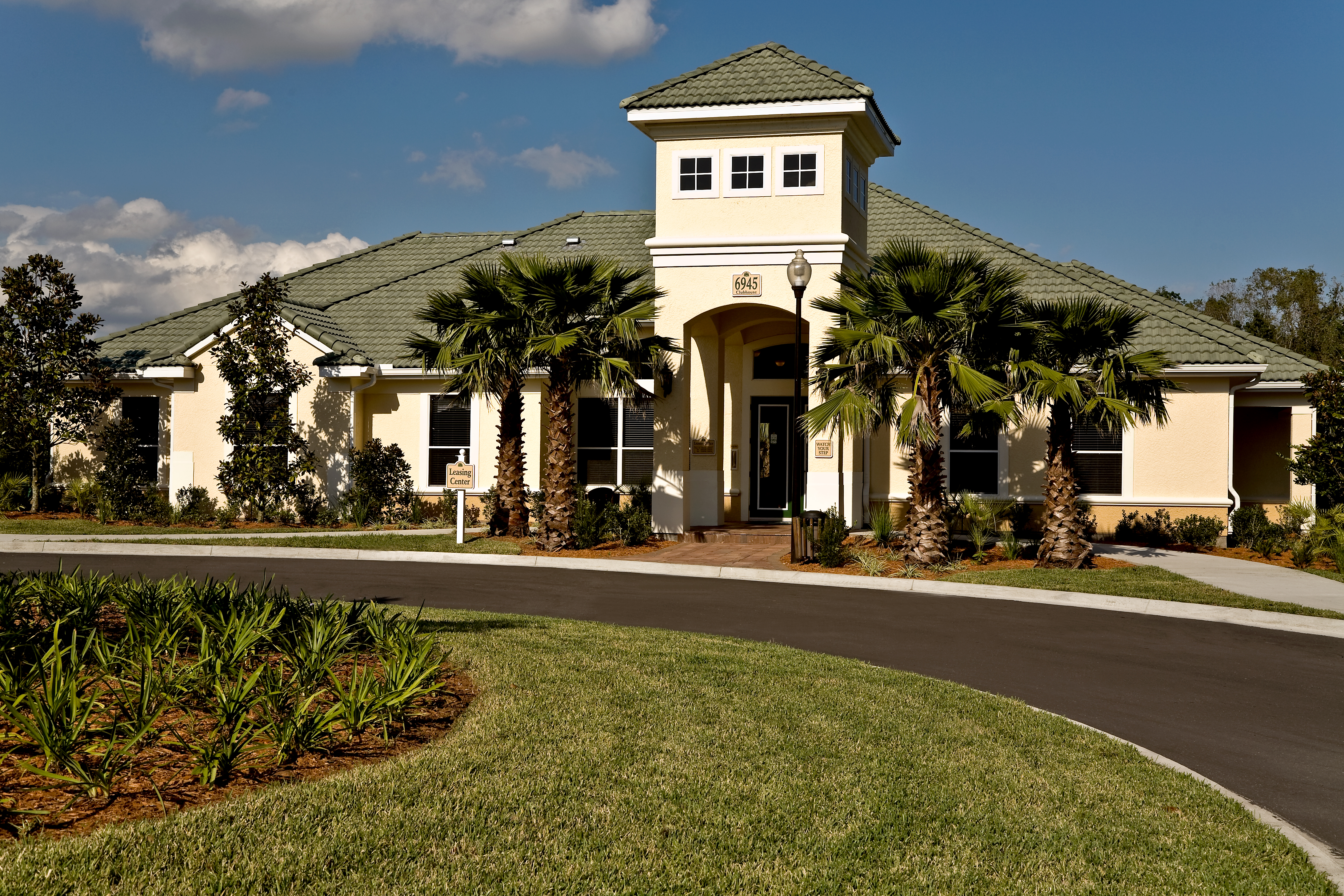 A large house with a tower and palm trees in front.