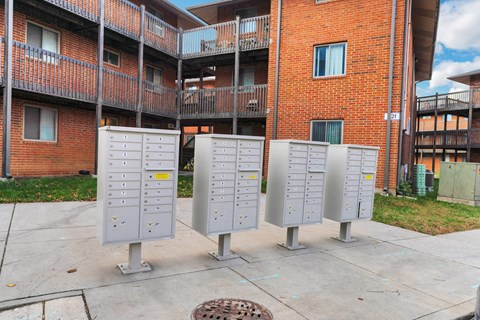 four metal mailboxes in front of a brick building