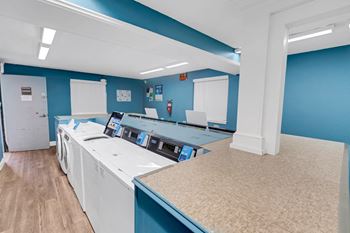 a laundry room with washers and dryers and blue walls and a counter top