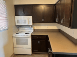 A kitchen with a white stove and black cabinets.