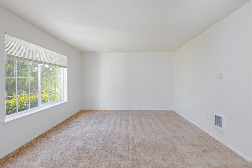 an empty room with a large window and carpet