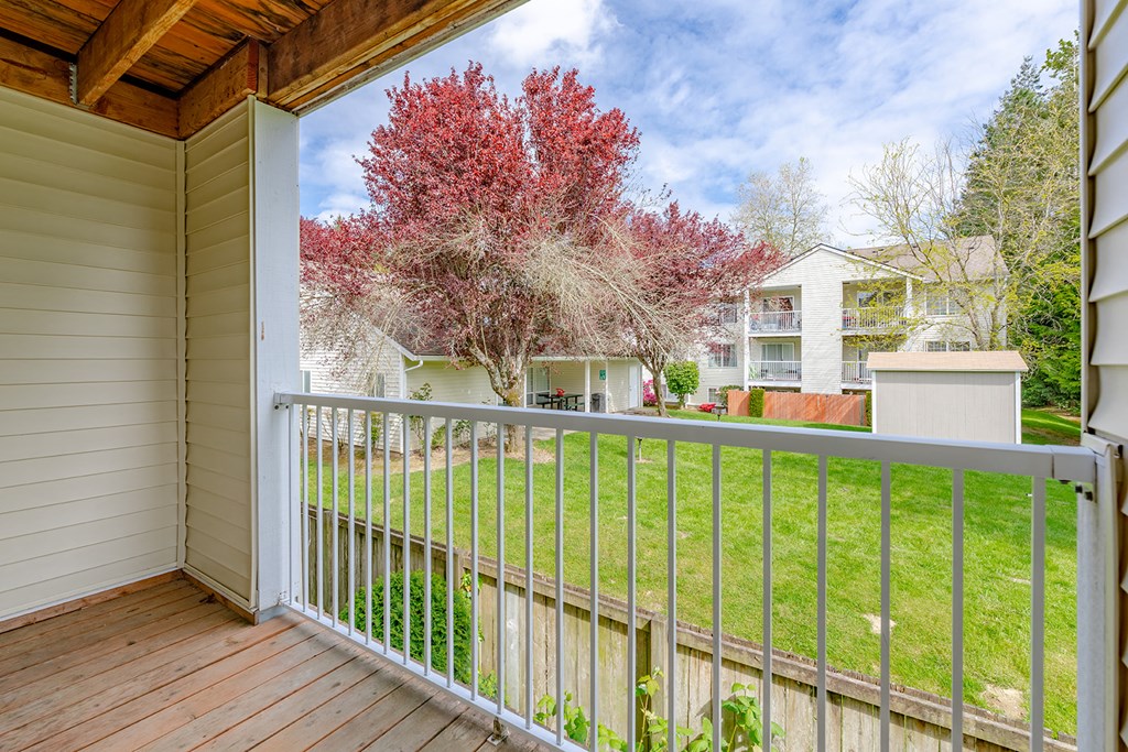 a balcony with a view of a yard and a tree