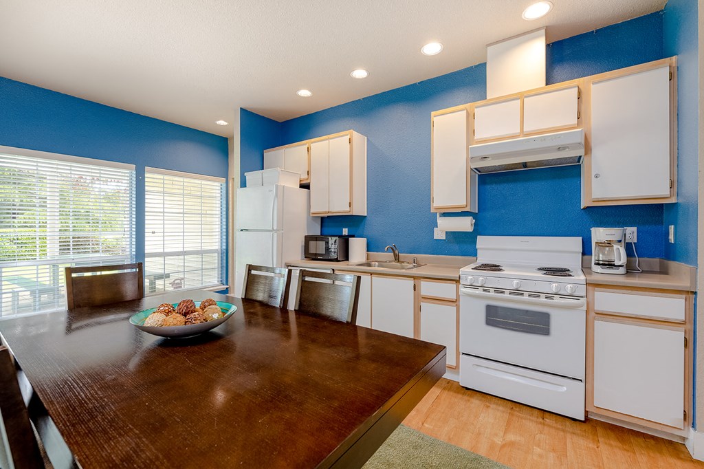 a kitchen with white appliances and a wooden table