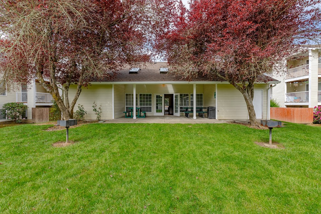 a house with a lawn and two trees in front of it