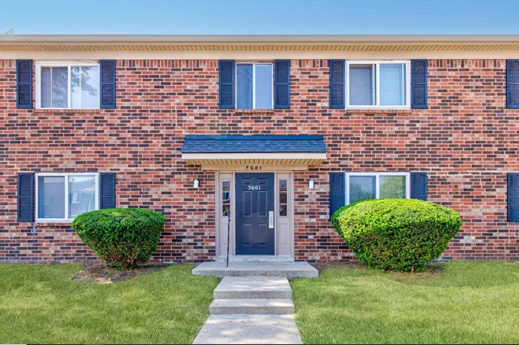 a red brick house with blue shutters and a blue awning
