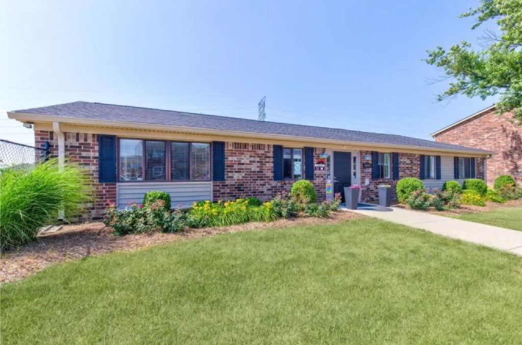 a brick building with blue shutters and a grassy yard in front of it