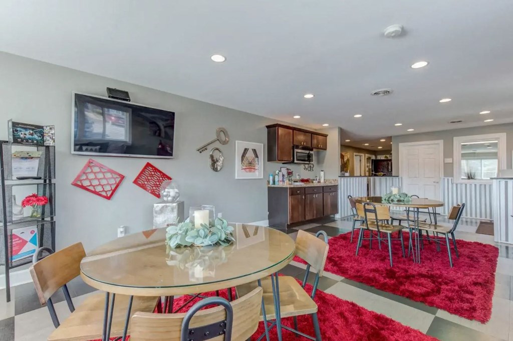 a dining area with a table and chairs and a kitchen in the background