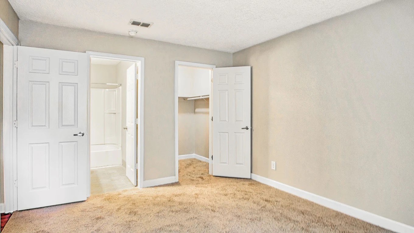 A room with two white doors and a carpeted floor.