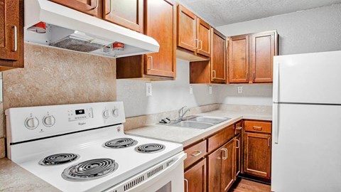 A kitchen with a white stove and wooden cabinets.