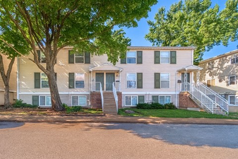 A two-story apartment building with a tree in front.