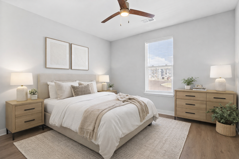 A bedroom with a bed, nightstands, and a ceiling fan.