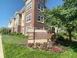 A brick building with a sign that says "Woodhurst Village" in front of it.