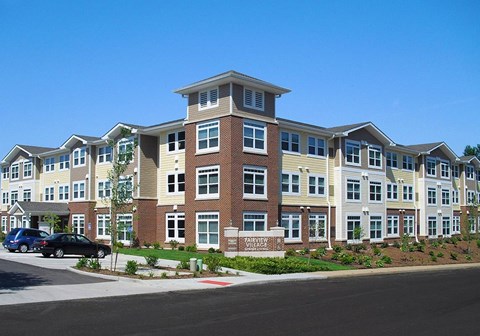 A large apartment complex with a parking lot in front.