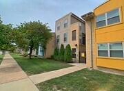 A yellow building with a brown door and windows.