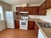 A kitchen with white appliances and wooden cabinets.