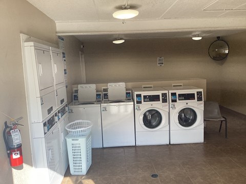 A laundry room with a washer and dryer on the wall and a fire extinguisher on the floor.