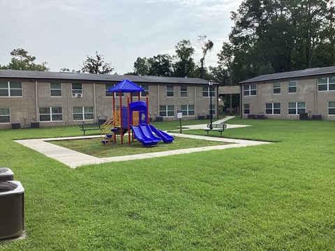 A playground with a blue slide and a yellow slide in the middle of a grassy area.