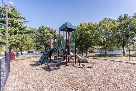 A playground with a green slide and a red fire hydrant.