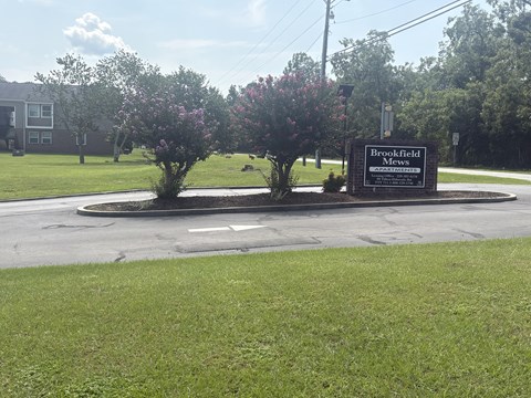 A sign for Brookfield Mews stands in front of a grassy area.