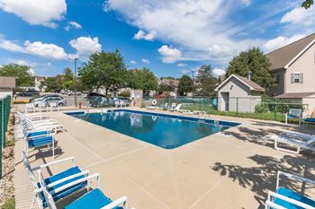 A large outdoor swimming pool surrounded by blue lounge chairs.