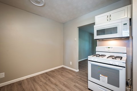 A kitchen with a white oven and microwave above it.
