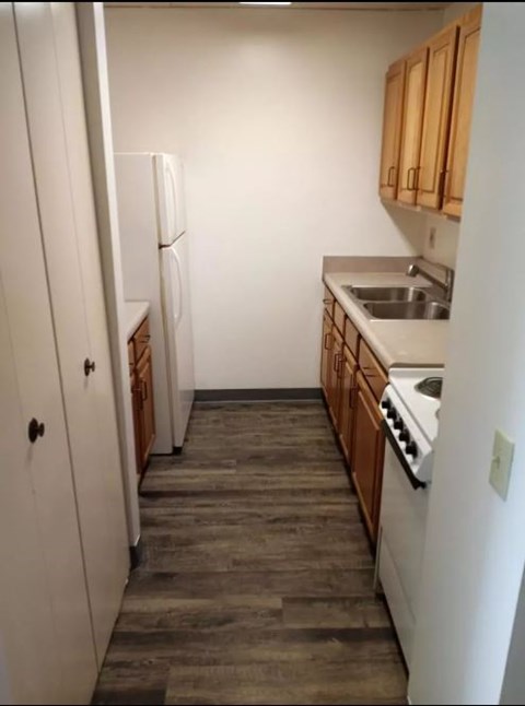 A kitchen with a white refrigerator and wooden cabinets.