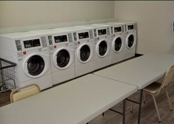 A row of white washing machines are lined up in a laundromat.