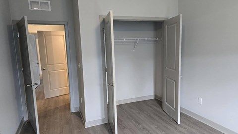 A room with a white door and a white closet with a shelf.