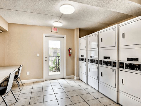 A laundry room with a washer and dryer on the right and a table and chairs on the left.