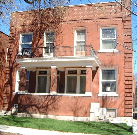 A red brick building with a balcony on the second floor.