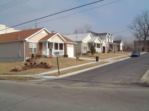A street view of a residential area with houses and a car parked on the side.