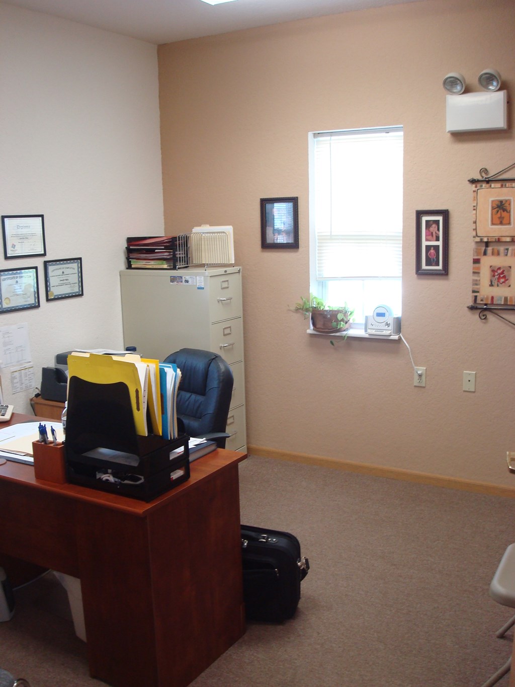 A brown desk with a yellow and black chair in front of it.