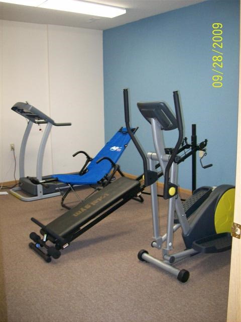 A gym with a treadmill, exercise bike and elliptical trainer.