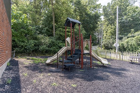 A playground with a red slide and a black roof.