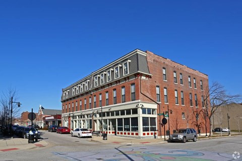 A red brick building with a white trimmed porch and a white awning with the word "HOTEL" on it.