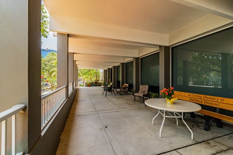 a long porch with tables and chairs and a large window