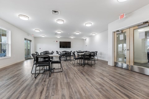 a conference room with tables and chairs and a tv on the wall