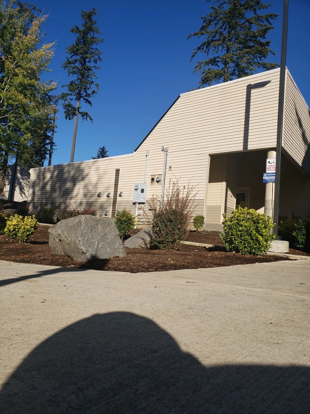 a view of the side of a building with a sidewalk and rocks