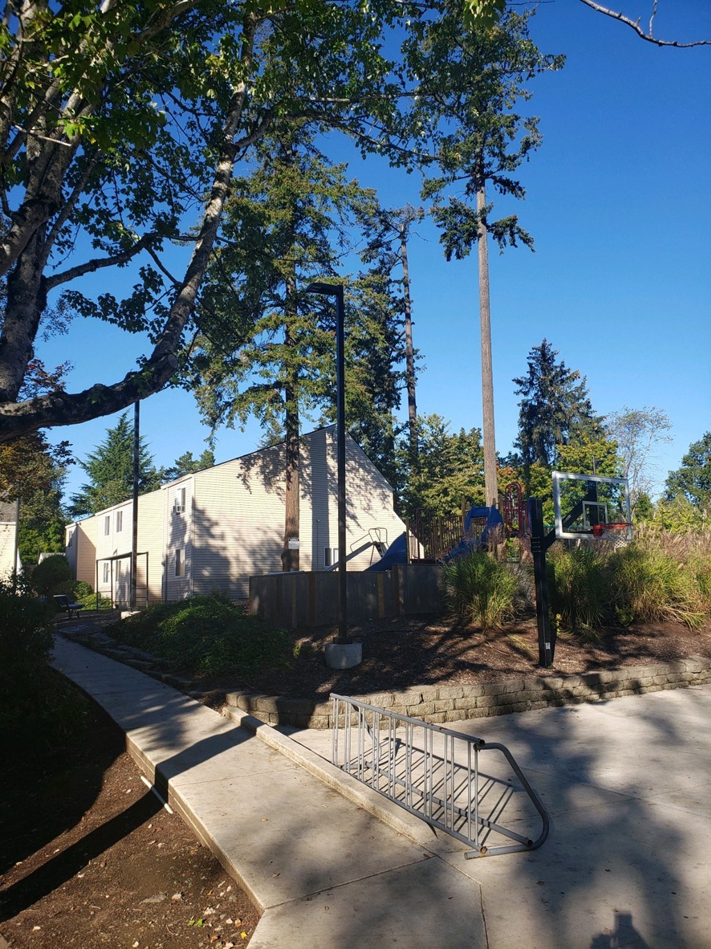 a building with a basketball court in front of it and trees