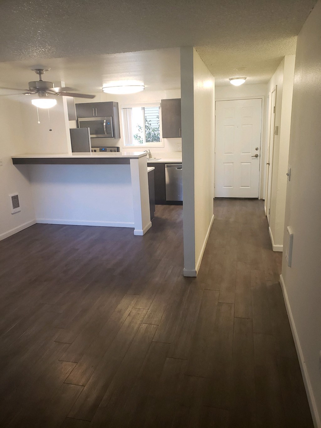 an empty living room and kitchen with wood flooring