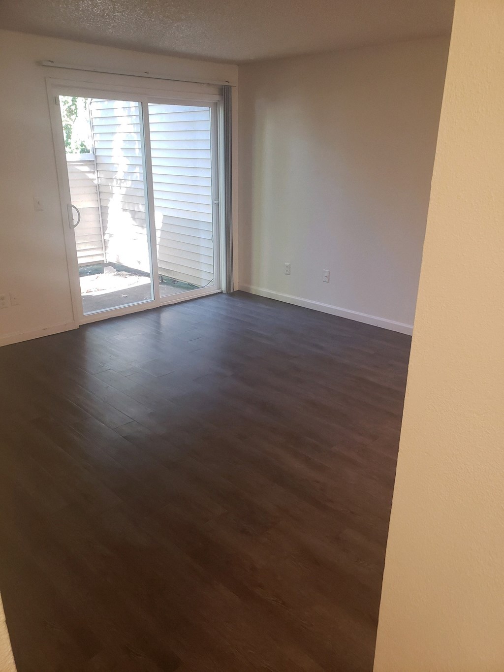 an empty living room with wood floors and a sliding glass door