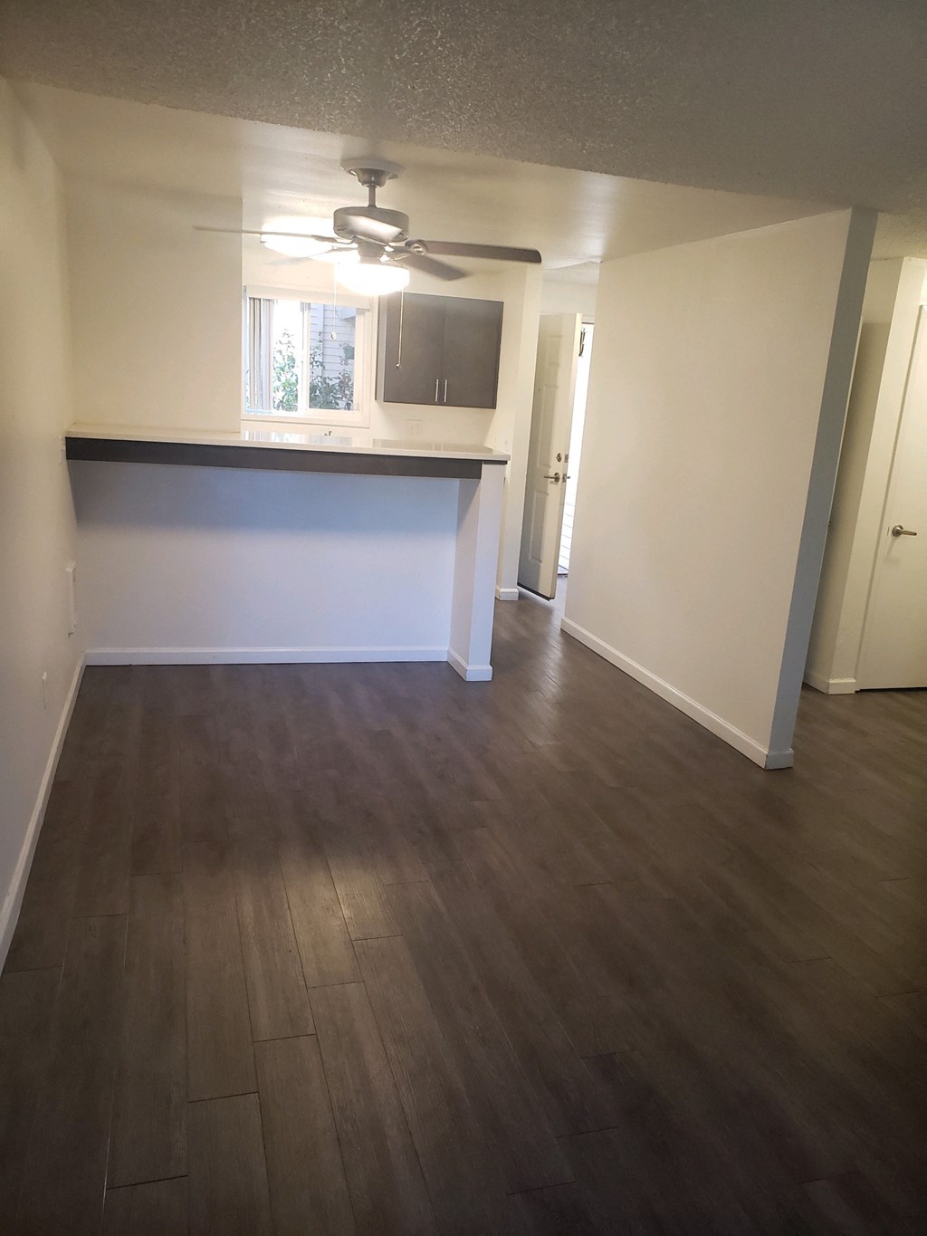 an empty living room with wood floors and a kitchen